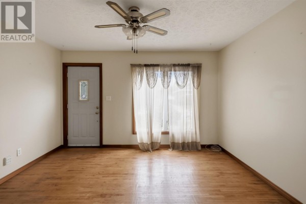 Living room with hardwood floors, a ceiling fan, and a front door with a window. - 165 Spadina Ave, Sault Ste  Marie