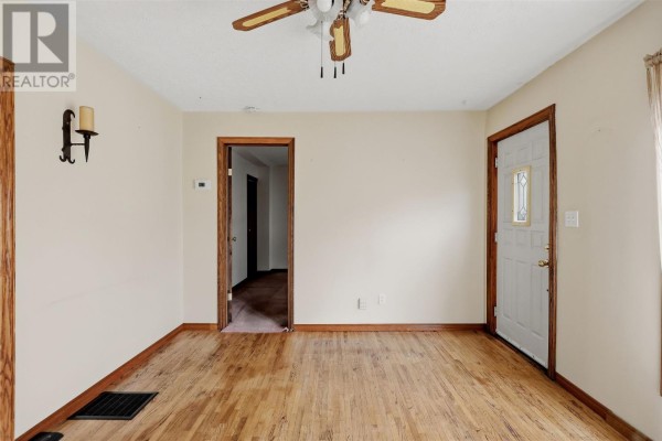 Living room with hardwood floors, ceiling fan, and doorway to hallway. - 165 Spadina Ave, Sault Ste  Marie