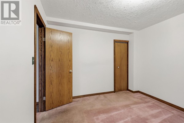 Bedroom with pink carpet, two wooden doors, and white walls. - 165 Spadina Ave, Sault Ste  Marie