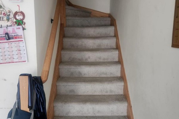 Carpeted stairs with a wooden handrail ascend between pale walls, a calendar visible on the left. - 20 - 165 Tapscott Road, Toronto