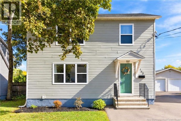Front view of a two-story gray house with a green door and a detached garage. - 165 West Lane, Moncton