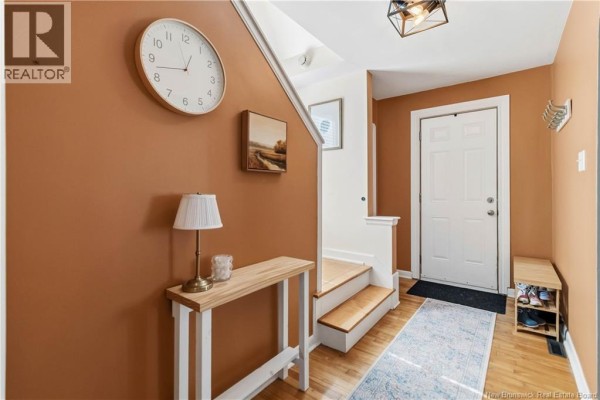 Entrance hallway with brown walls, a wooden console table, and stairs leading up. - 165 West Lane, Moncton