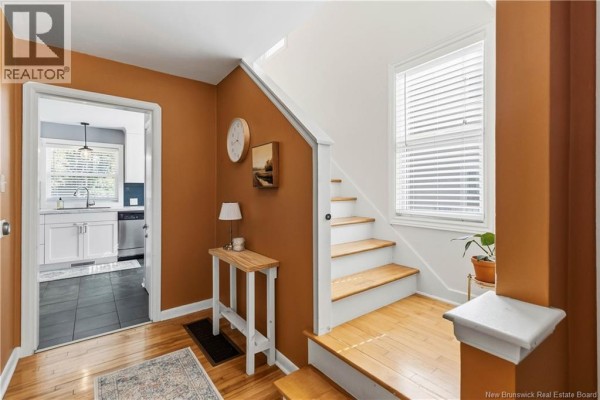 Interior view of an entryway with brown walls, a staircase, and an open doorway to the kitchen. - 165 West Lane, Moncton