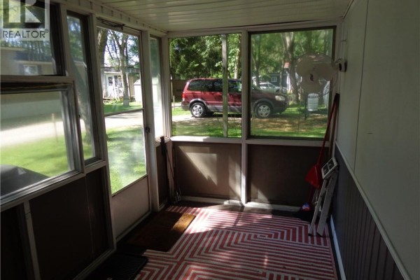 Interior of a screened-in porch with a red and white geometric rug and views of the outdoors. - 1652 Puddicombe Road Unit# 422, New Hamburg