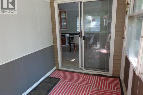 View from the screened-in porch through sliding glass doors into a dining area. - 1652 Puddicombe Road Unit# 422, New Hamburg