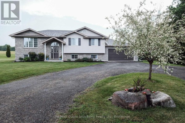 Close-up of the house entrance with double doors, arched window, and stone facade. - 16566 Highway 2, Quinte West