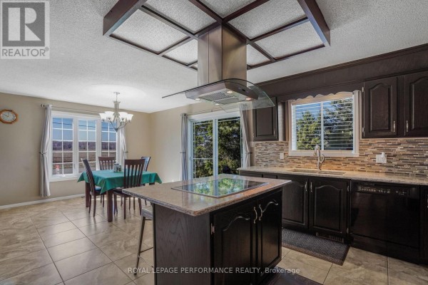 A kitchen island with a stovetop connects to a dining area with a table and chairs, and a sliding glass door. - 1658 600 Route W, The Nation