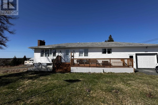 Front view of the house with white siding, a wooden deck, and an attached garage. - 1659 Ns-206 Highway, West Arichat