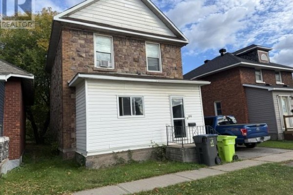 Front view of a two-story house with stone and white siding and a blue pickup truck. - 166 Hudson St, Sault Ste  Marie