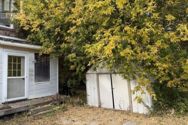 Exterior view of a shed behind a white-sided addition, surrounded by fallen leaves. - 166 Hudson St, Sault Ste  Marie