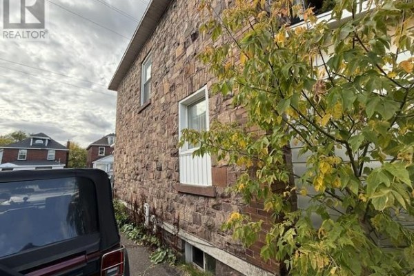 Side of a stone house with a window and a tree with yellowing leaves in the foreground. - 166 Hudson St, Sault Ste  Marie