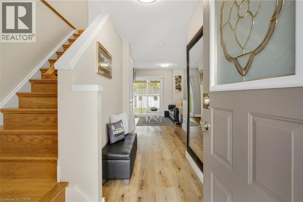 Foyer with a staircase, wood floors, black bench, and view into the living area. - 166 Martindale Crescent, Brampton