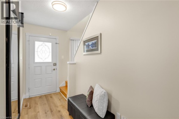 Interior view of a foyer showing a door, bench, artwork, and staircase. - 166 Martindale Crescent, Brampton