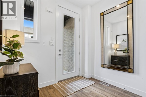 Entryway with white walls, wood-look flooring, and a decorative mirror. - 166 Mount Albion Road Unit# 25, Hamilton