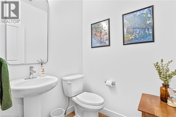 Powder room with a white pedestal sink, toilet, and framed artwork. - 166 Mount Albion Road Unit# 25, Hamilton
