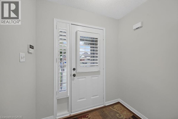 Interior front entryway with a white door, side window with shutters, and beige walls. - 166 Toby Crescent, Hamilton