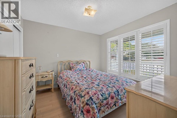 Bedroom with a queen-sized bed, wooden furniture, and plantation shutters on the windows. - 166 Toby Crescent, Hamilton