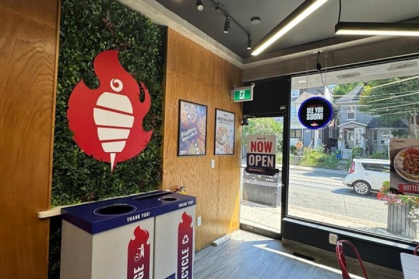 Interior view of a restaurant with green wall, wooden panels, and a large red shawarma logo. - 1660 Queen Street W, Toronto