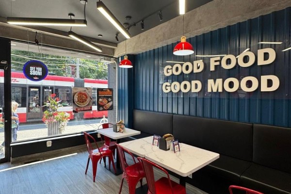 Restaurant seating area with tables, red chairs, and a large window showing a streetcar. - 1660 Queen Street W, Toronto