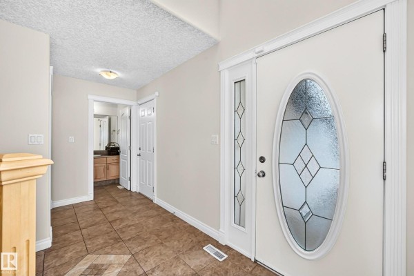 Interior view of the beige entryway with tiled floors and doors leading to other rooms. - 16619 72 St Nw, Edmonton