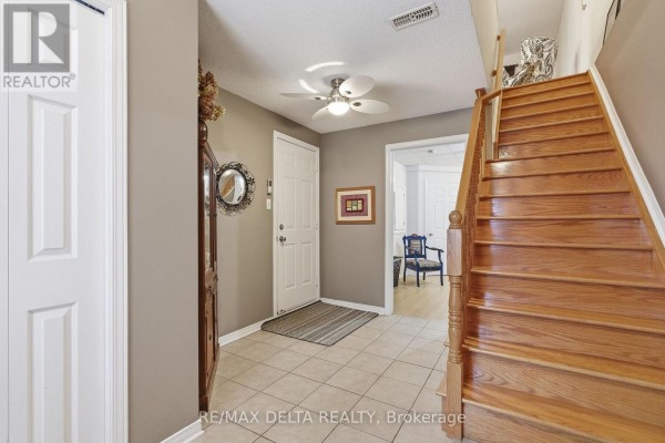 Interior view of townhouse foyer with tiled floor, a grandfather clock, and wooden staircase. - 1667 Manon Street, Clarence Rockland