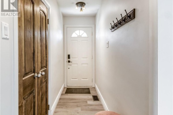 Interior view of a narrow entryway with a white front door and double wooden doors. - 1668 Latimer Crescent, Sudbury