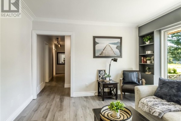 Living room with grey walls, white trim, a large window, and built-in bookshelves. - 1668 Latimer Crescent, Sudbury