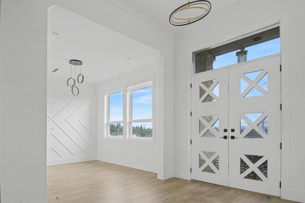 Entryway with decorative door, large windows, and modern light fixtures. - 16685 15a Avenue, Surrey