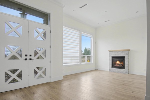 Cozy corner of the living room featuring a fireplace and large windows for natural light. - 16685 15a Avenue, Surrey