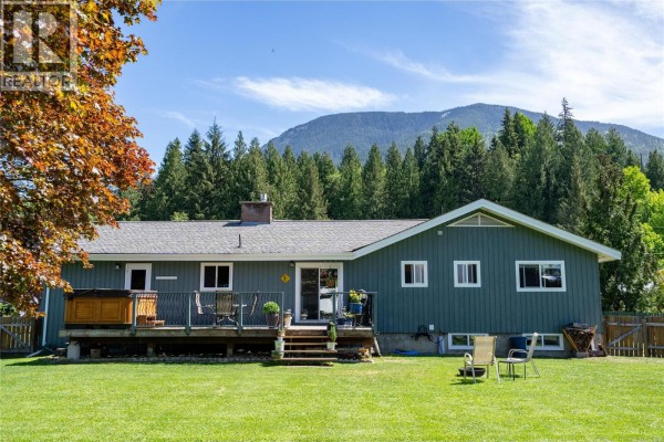 Interior of a spacious, open garage with storage shelves, tools, and a door leading to stairs. - 1669 Hiob Road, Revelstoke