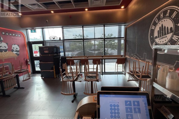View of restaurant tables with stools, a counter, and large windows with blinds. - 167 - 390 Silver Star Boulevard, Toronto