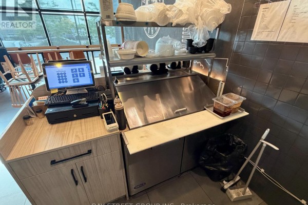 Close-up of a restaurant counter with a POS system, coffee station, and stainless steel ice bin. - 167 - 390 Silver Star Boulevard, Toronto