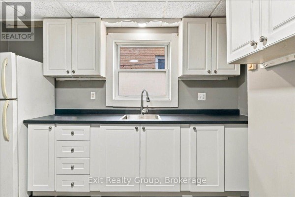 Kitchen with white cabinets, dark countertops, and a double sink below a window. - 167 Marmora Street, Quinte West