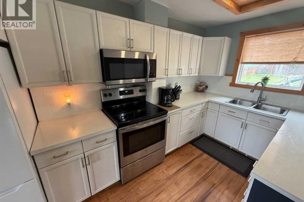 Open concept kitchen and dining area with wood floors and white cabinetry. - 167 Sunwapta Drive, Hinton
