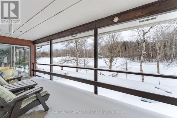 Covered porch with chairs overlooking a snow-covered yard and trees. - 16735 Mississauga Road, Caledon