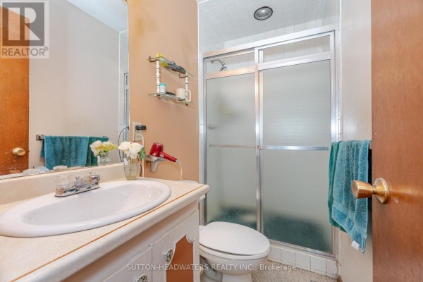 Bathroom with a vanity, sink, toilet, and a sliding glass shower stall. - 16735 Mississauga Road, Caledon
