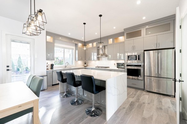 Modern kitchen with gray cabinetry, quartz island, and stainless steel appliances. - 16755 16a Avenue, Surrey
