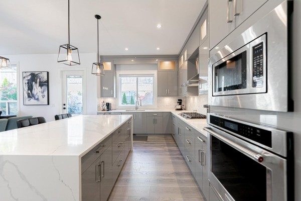 Close-up of kitchen with ample counter space, pendant lighting, and built-in appliances. - 16755 16a Avenue, Surrey