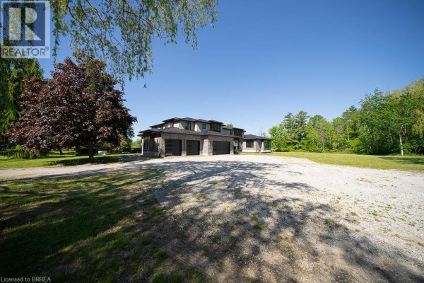 View of the house exterior with a gravel driveway leading to a four-car garage. - 1679 Highway 6, Port Dover
