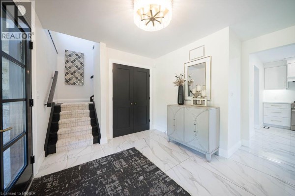 Foyer with marble tile flooring, dark gray double doors, and a mirrored console table. - 1679 Highway 6, Port Dover