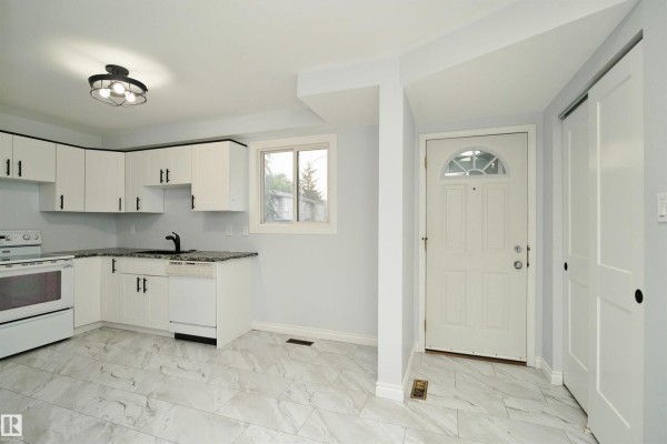 Kitchen and entryway with a white front door, white closet doors, and modern lighting. - 1679 Lakewood Rd S Nw, Edmonton