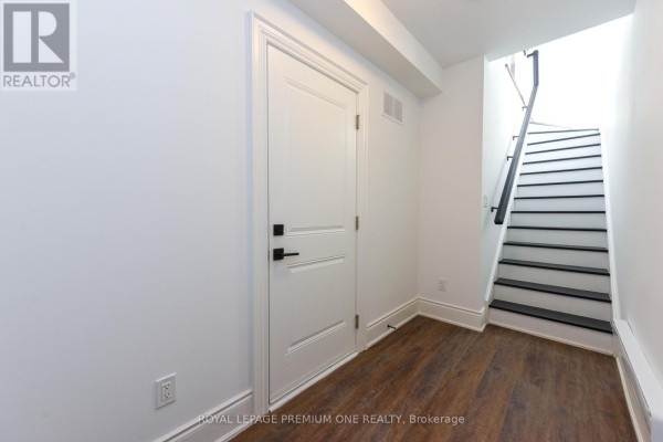 Hallway inside the townhouse with wood-look flooring, white walls, and a staircase. - 168 - 56 Lunar Crescent, Mississauga