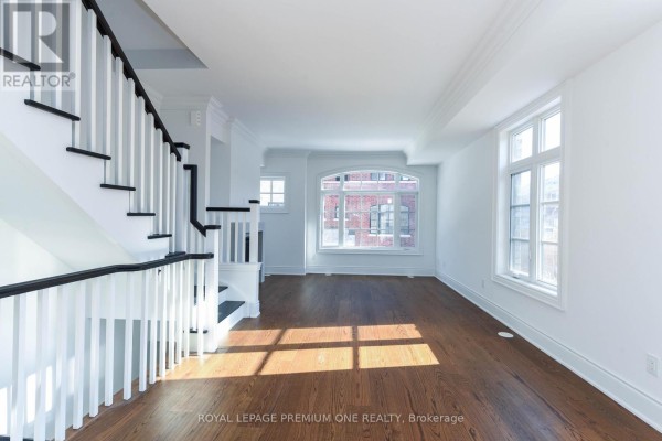 Living room with a staircase, dark wood floors, white walls, and large windows. - 168 - 56 Lunar Crescent, Mississauga