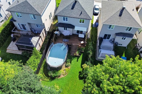 Aerial view of the front of a modern house with stone and beige siding, showing the driveway and surrounding trees. - 168 Rue De La Lobo, Gatineau