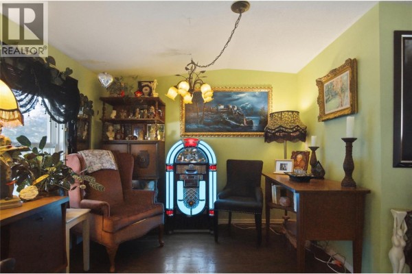A corner room with a red armchair, black chair, a vintage jukebox, and wall art. - 1680 Lac Le Jeune Road Unit# 22, Kamloops