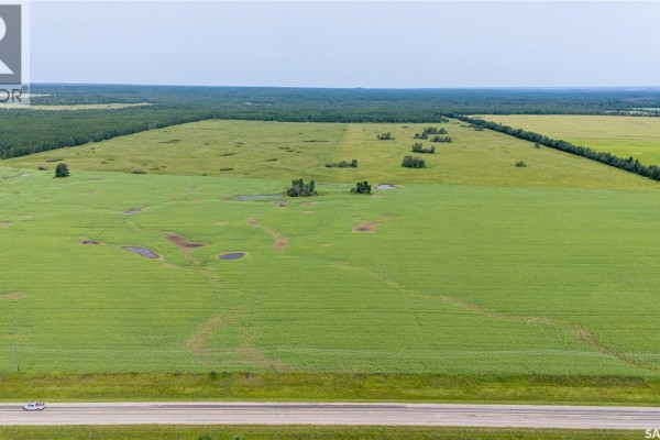 Expansive aerial view of a large green field with natural water features and surrounding treed areas. - 1685 Acres Mixed Use Land Near Spiritwood, Medstead Rm No 497