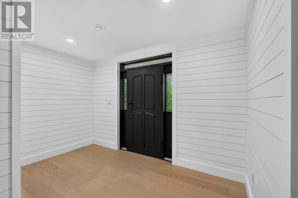 Interior entryway with white shiplap walls, light wood floor, and a black front door. - 1685 Kingston Road, Rte 323, Kingston