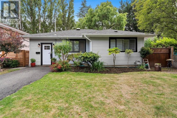 Front view of a light grey house with white trim, windows, and landscaping. - 1685 Midgard Ave, Saanich