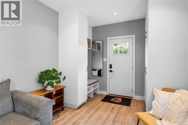 Interior entrance hallway with light wood floors, white cabinets, and grey walls. - 1685 Midgard Ave, Saanich