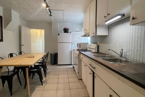 Kitchen with white cabinets, stainless steel appliances, and a long wooden dining table. - 169 Gladstone Avenue, Toronto